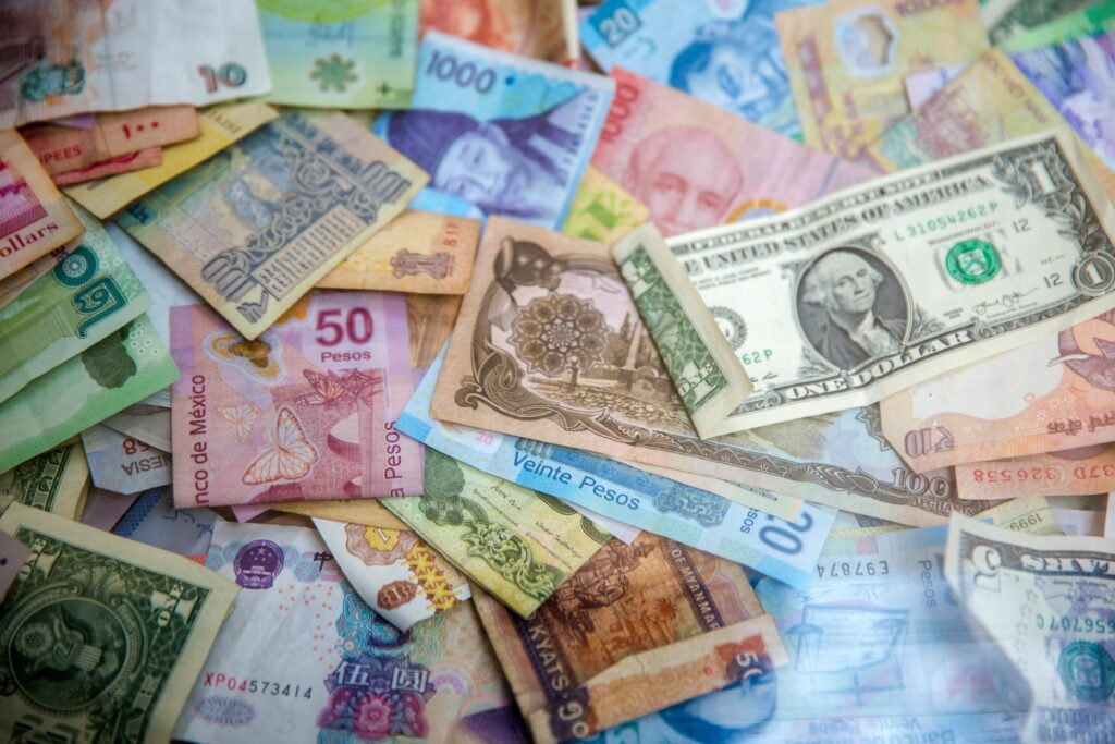 알록달록한 여러 나라의 지폐들이 이리저리 흩어진 채로 펼쳐져 있는 이미지입니다. 